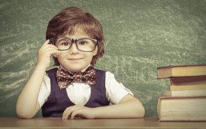 Cheerful smiling little boy sitting at the table. Looking at camera School concept